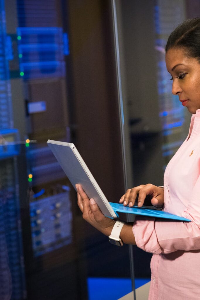 A focused software engineer working on a laptop in a server room, reflecting dedication in tech.