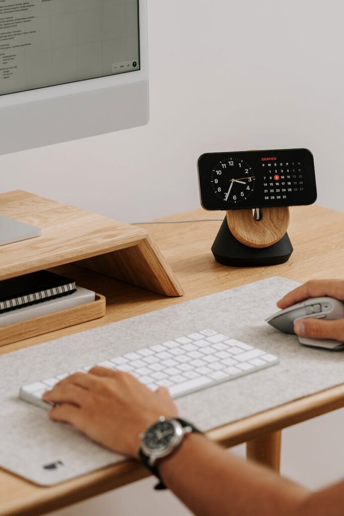 A clean and modern desk setup featuring a computer, clock, and accessories in a home office.