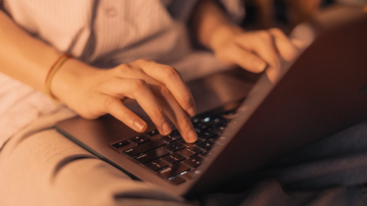 Close-up of hands typing on a laptop in a cozy home setting, perfect for remote work.